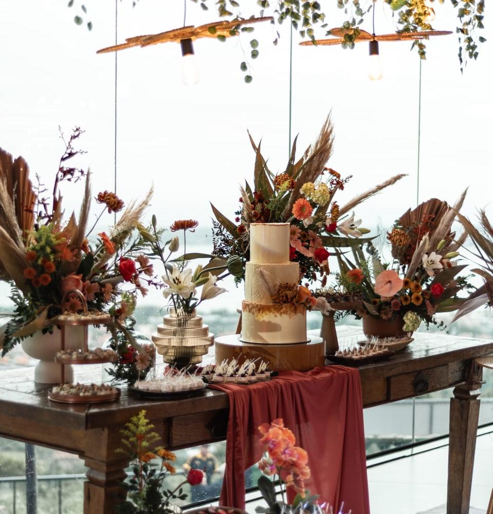 Mesa de doces com arranjos secos suspensos, montada sobre a água