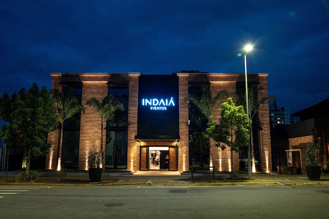 Fachada iluminada do Indaiá em Joinville ao anoitecer.