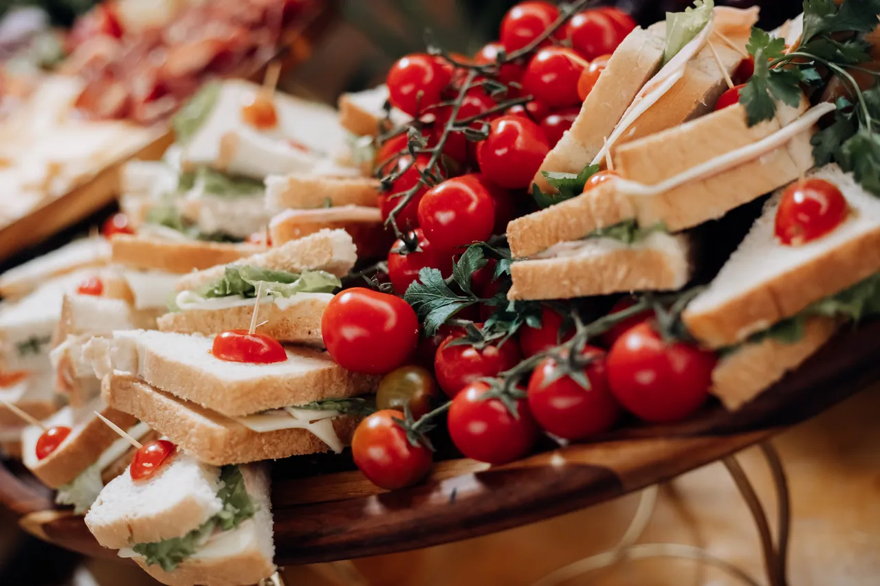 Canapés, tomates e queijos preparados para a recepção de um evento corporativo.