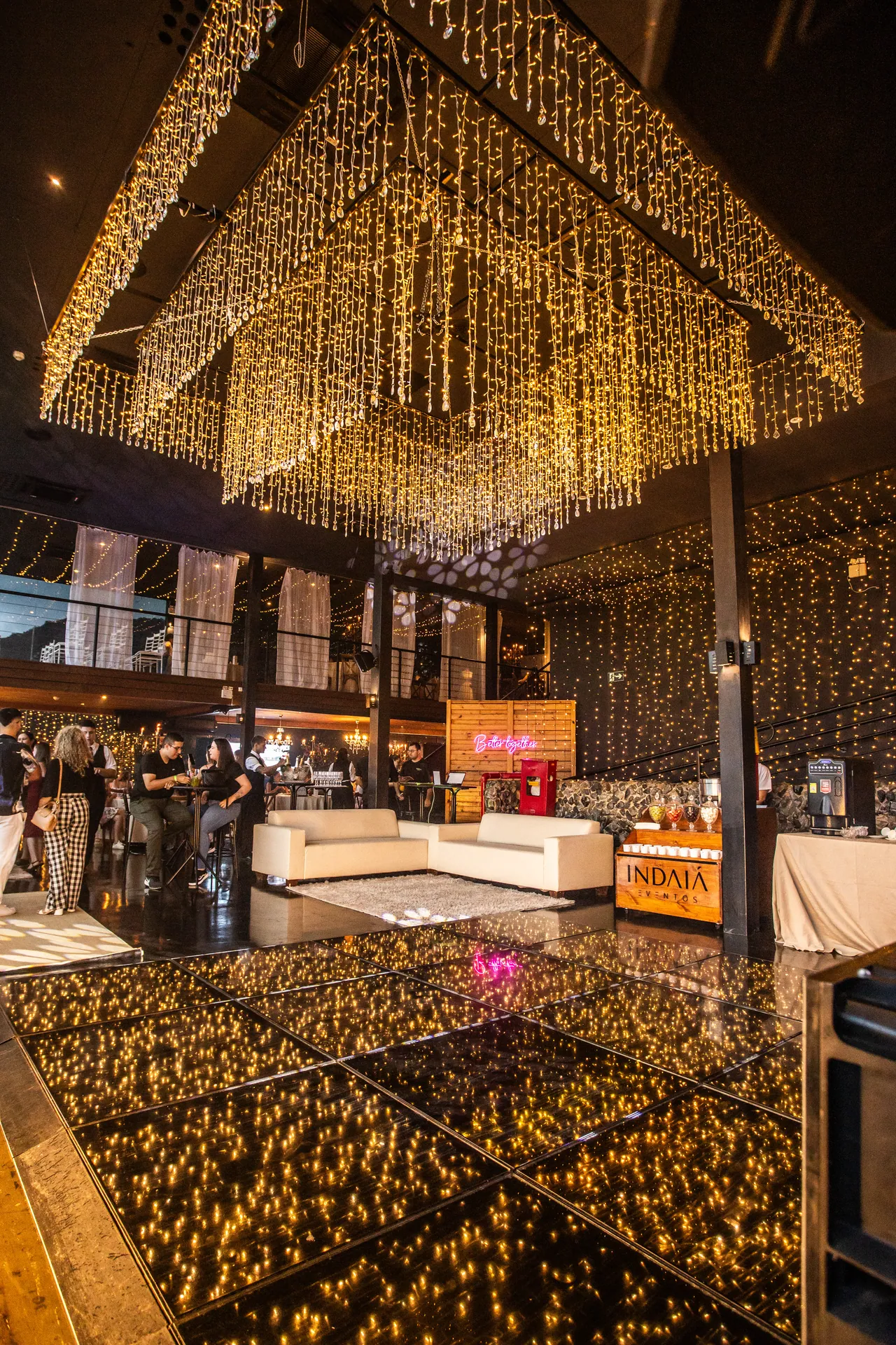 Salão do Indaiá em Itapema com iluminação dourada e ambientes preparados para receber eventos.