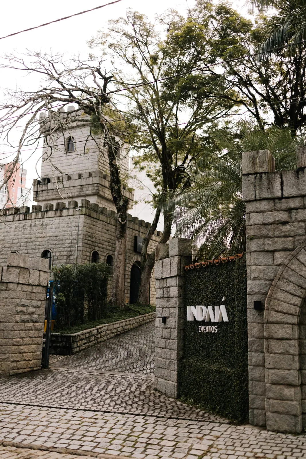Entrada do castelo do Indaiá em Blumenau, com torre de pedra e jardim.