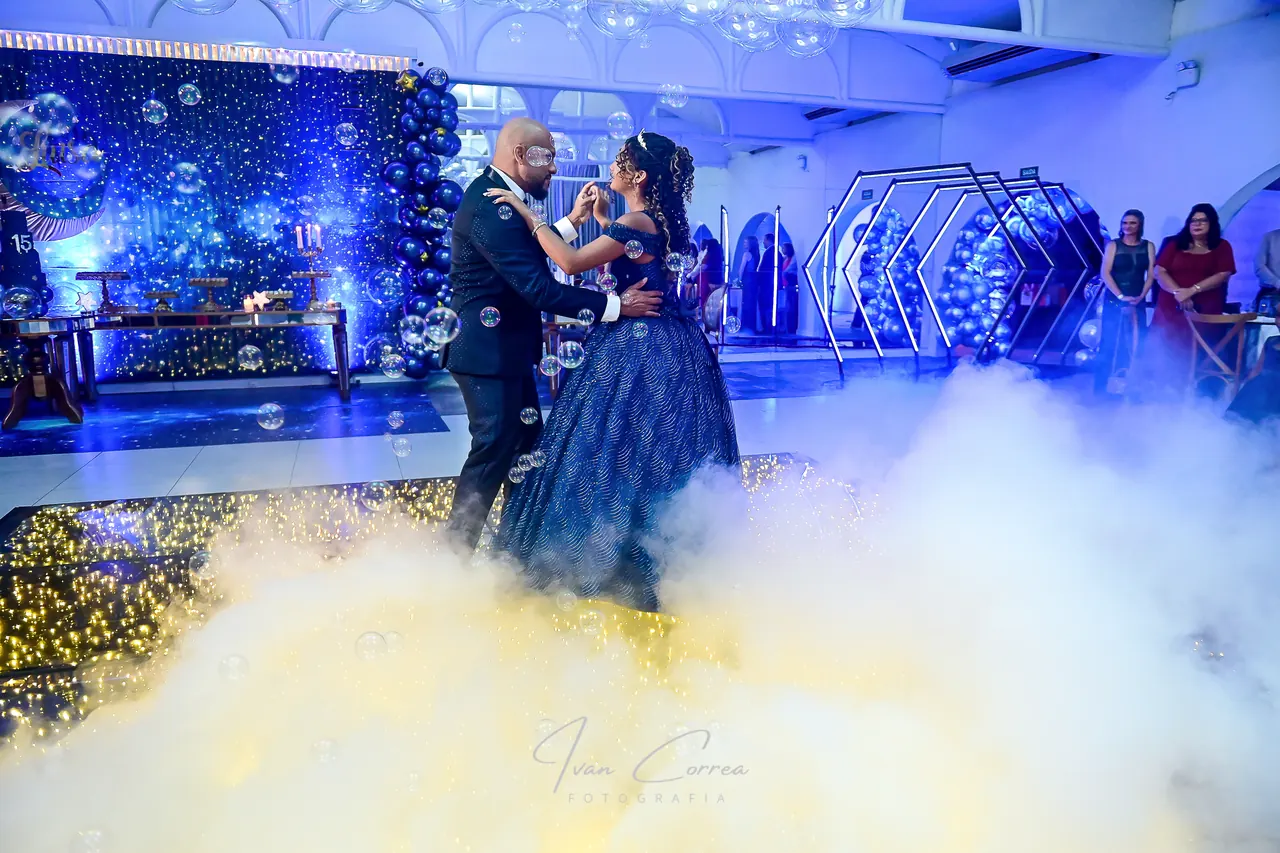 Debutante e acompanhante dançam sob luzes azuis e uma névoa baixa no Espaço Cristal.